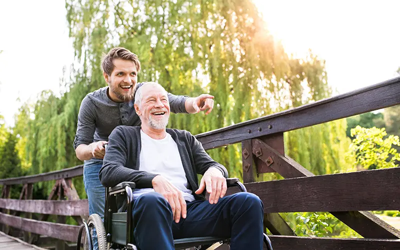 man pushing man in wheelchair